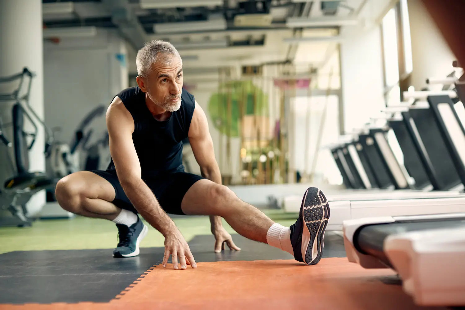 Active middle-aged man stretching in a modern gym, representing recovery and rejuvenation benefits of PRGF therapy in Farmington Hills